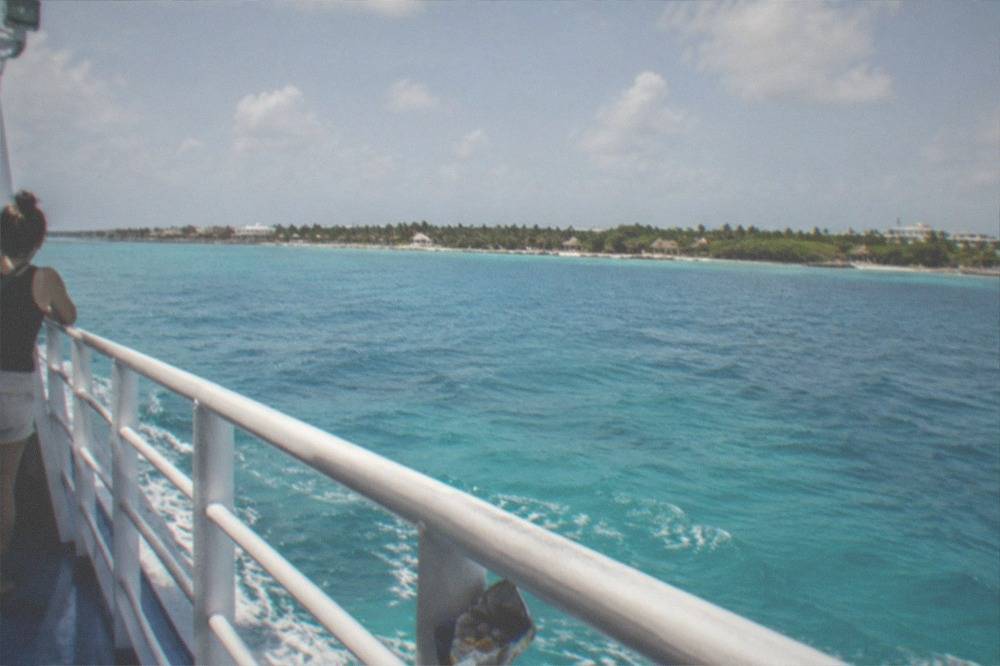 Turquoise Caribbean water seen from a ferry deck with an island on the horizon