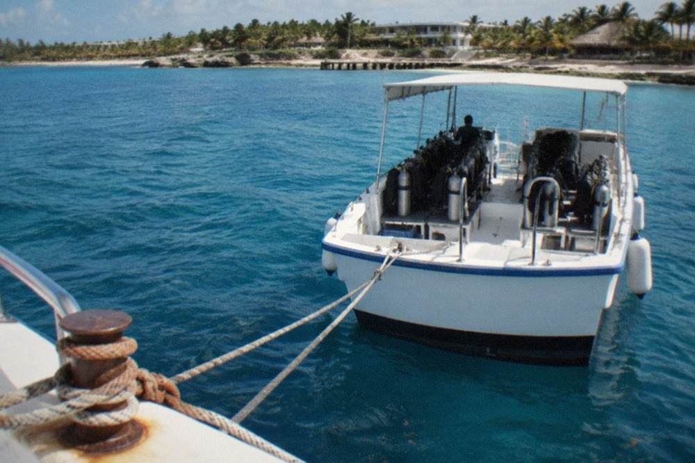 A dive boat moored over clear blue Caribbean water near a coral reef