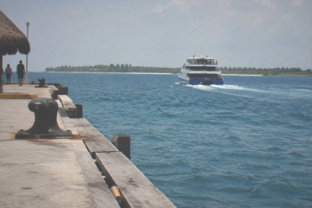 A passenger ferry crossing open Caribbean water toward an island coastline