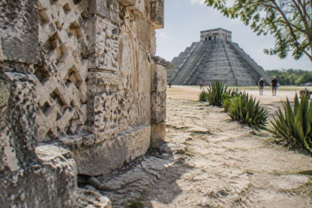 Carved stone facade of a Maya pyramid with lattice decoration under an open sky
