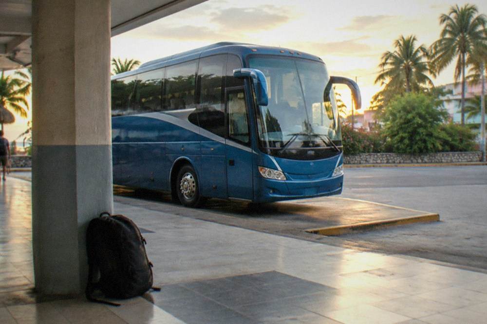Blue first-class tour bus parked at a station platform in evening light