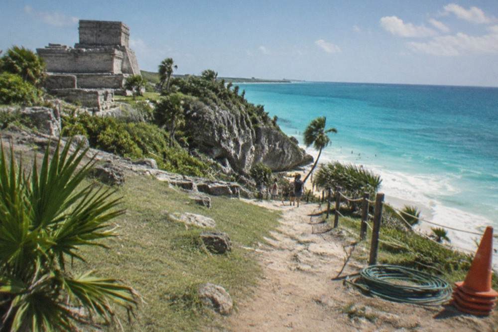 Turquoise Caribbean water and sky seen from a grassy clifftop with stone ruins