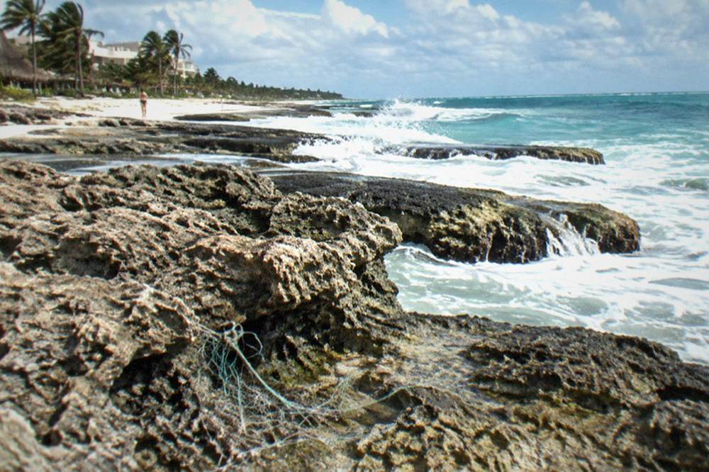 Rocky shoreline and clear shallow water at an exposed eastern beach with breaking waves