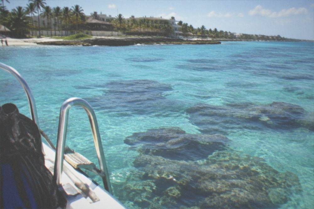 Snorkel boat anchored over a shallow coral reef with visible underwater coral heads
