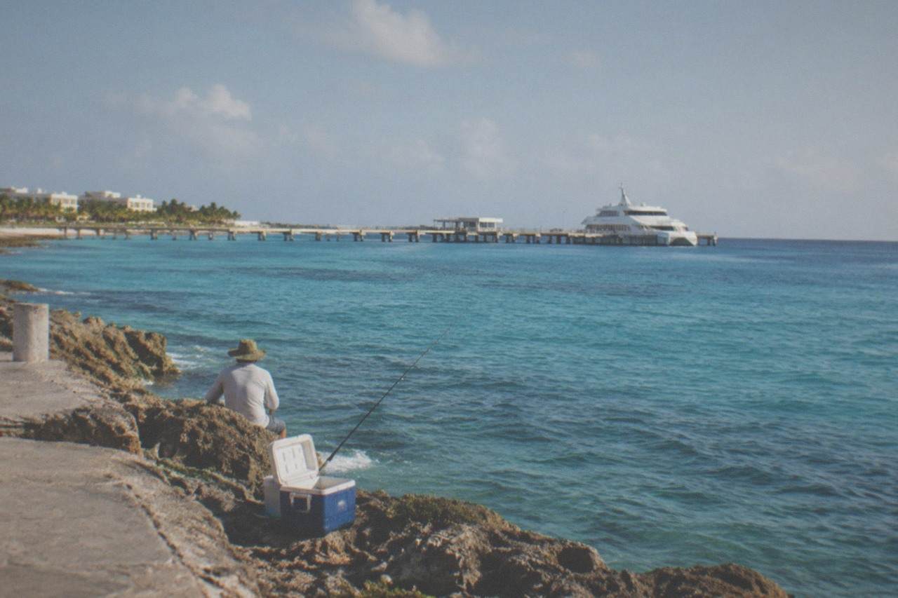 Calm turquoise water along a Caribbean island shoreline with a passenger ferry at a distant pier
