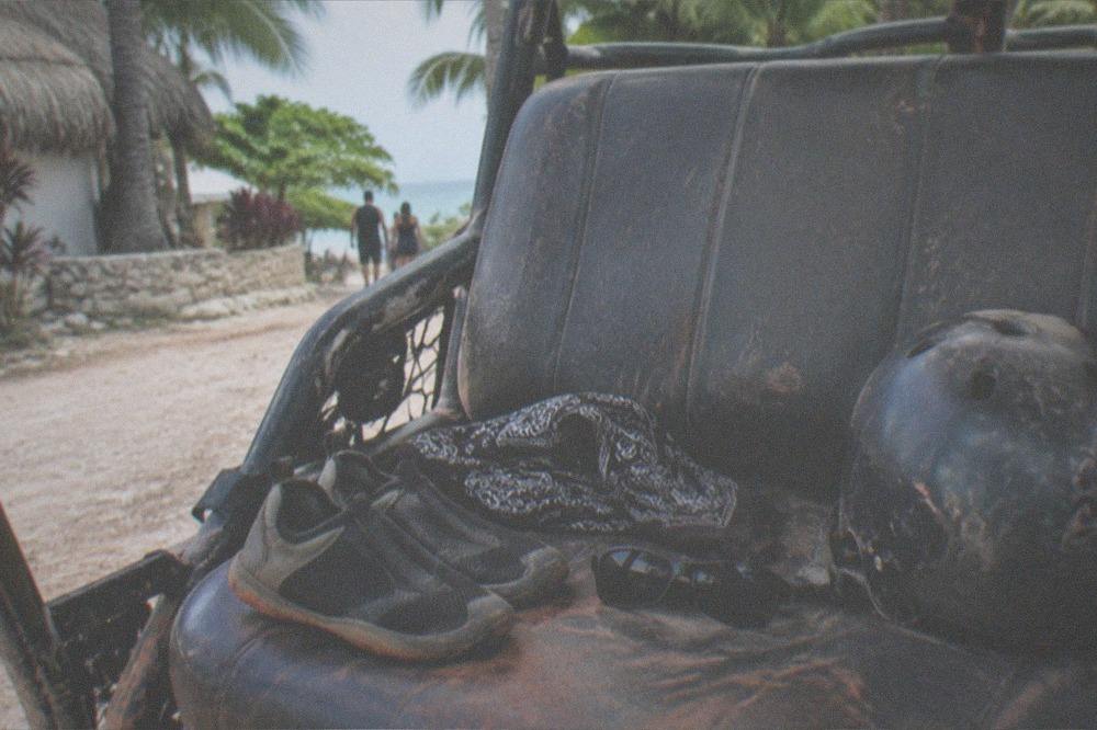 A bandana, sunglasses and water shoes laid out on a car seat before a jungle tour