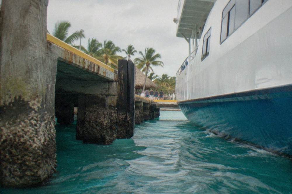 Passenger ferry docked at a Caribbean pier with turquoise water and palm trees