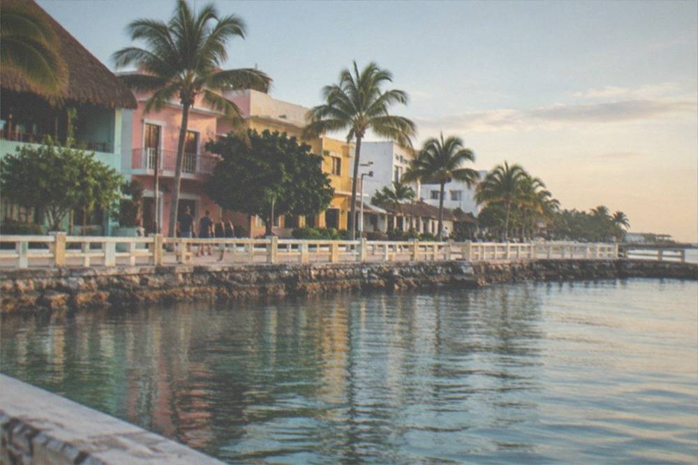 Waterfront promenade with colorful storefronts and a calm harbor in the background