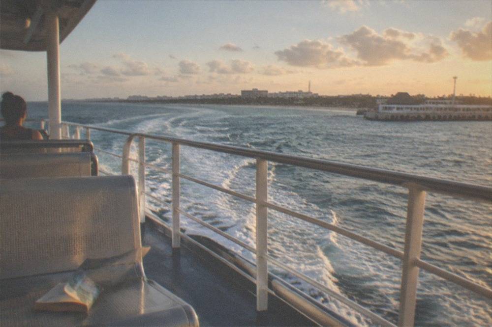 Passenger ferry crossing open Caribbean water with Cozumel's coastline visible ahead