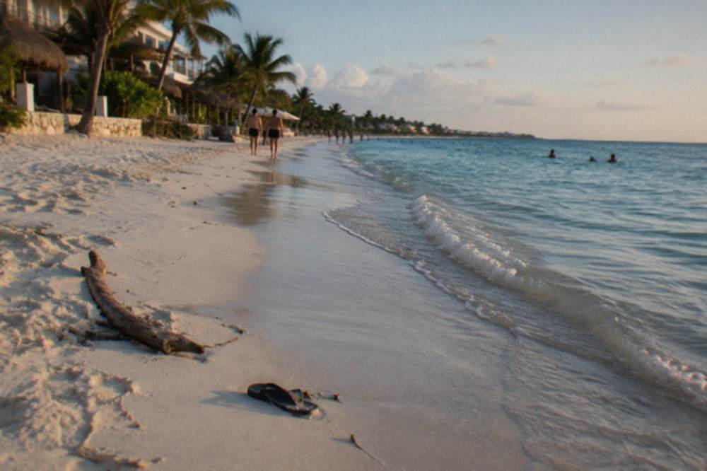 A wide sandy beach curving along the Caribbean shore under a clear blue sky