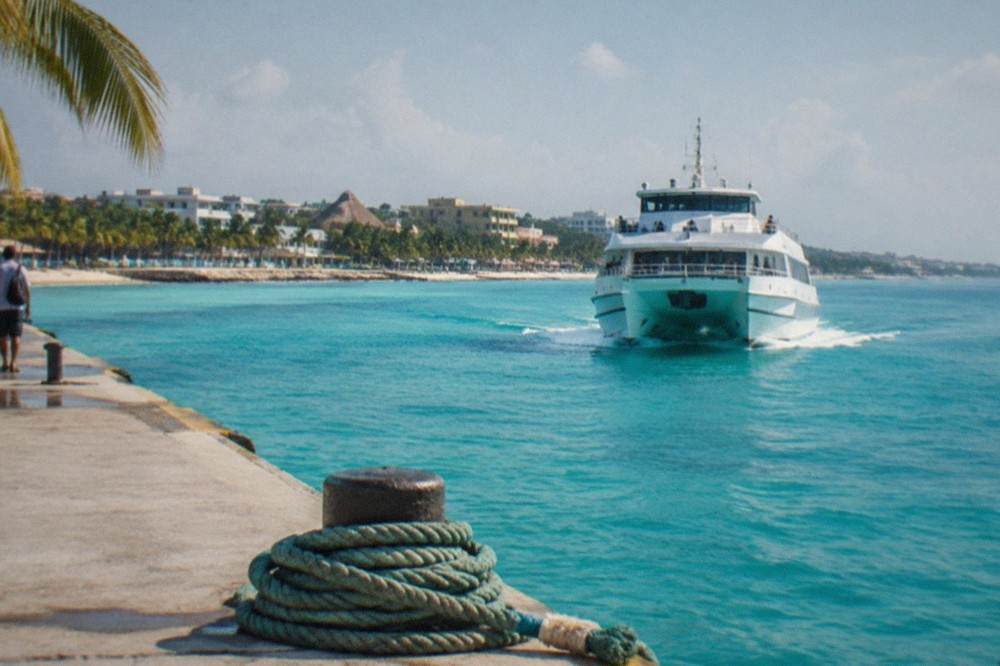 Passenger ferry approaching a dock on turquoise water with palm trees on shore
