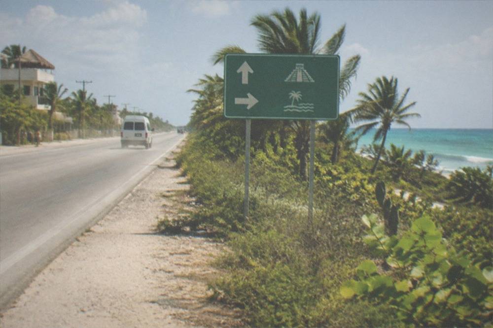 Highway road sign pointing toward Cancun and Tulum under a clear sky