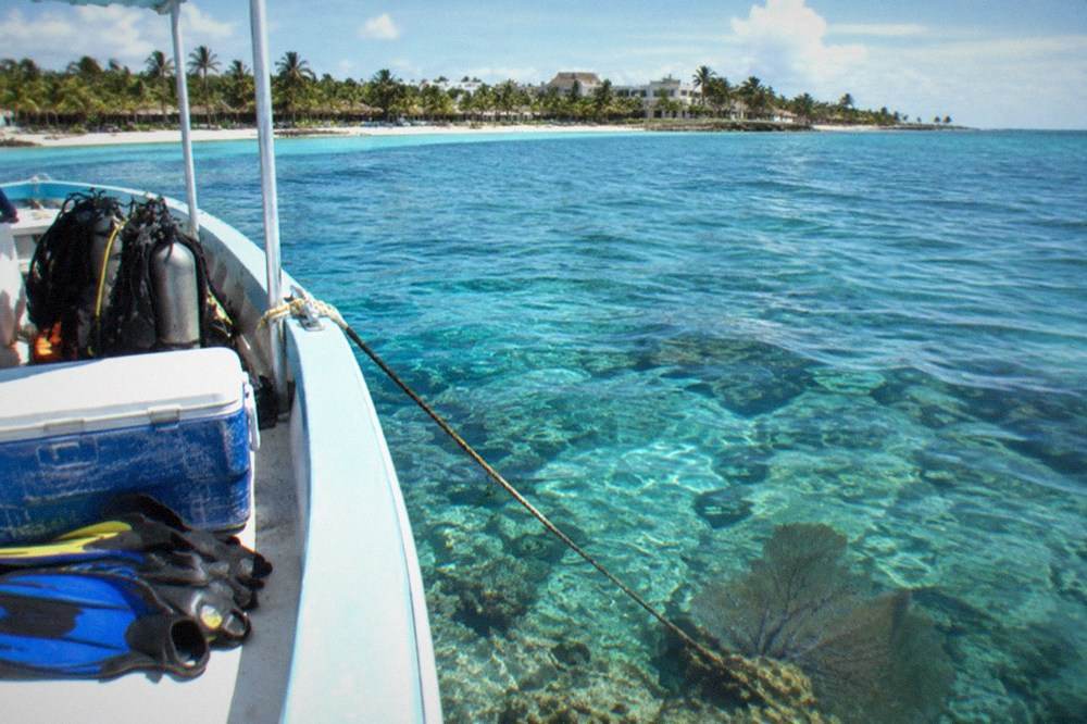 A boat anchored over a shallow coral reef in clear blue water